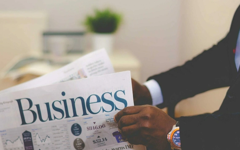 man-reading-newspaper-titled-business
